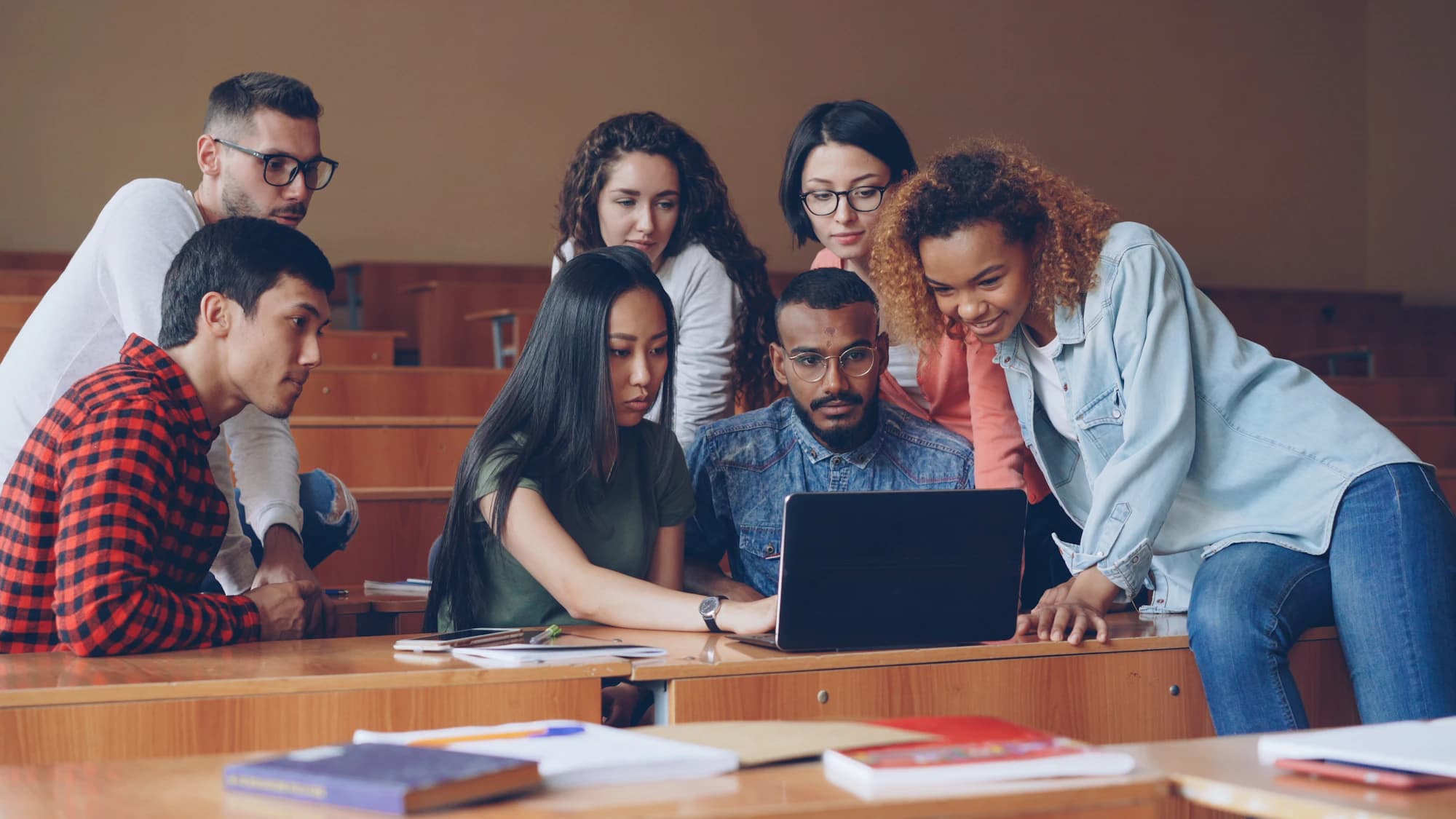 A diverse group of students collaborating around a laptop in a mentorship session